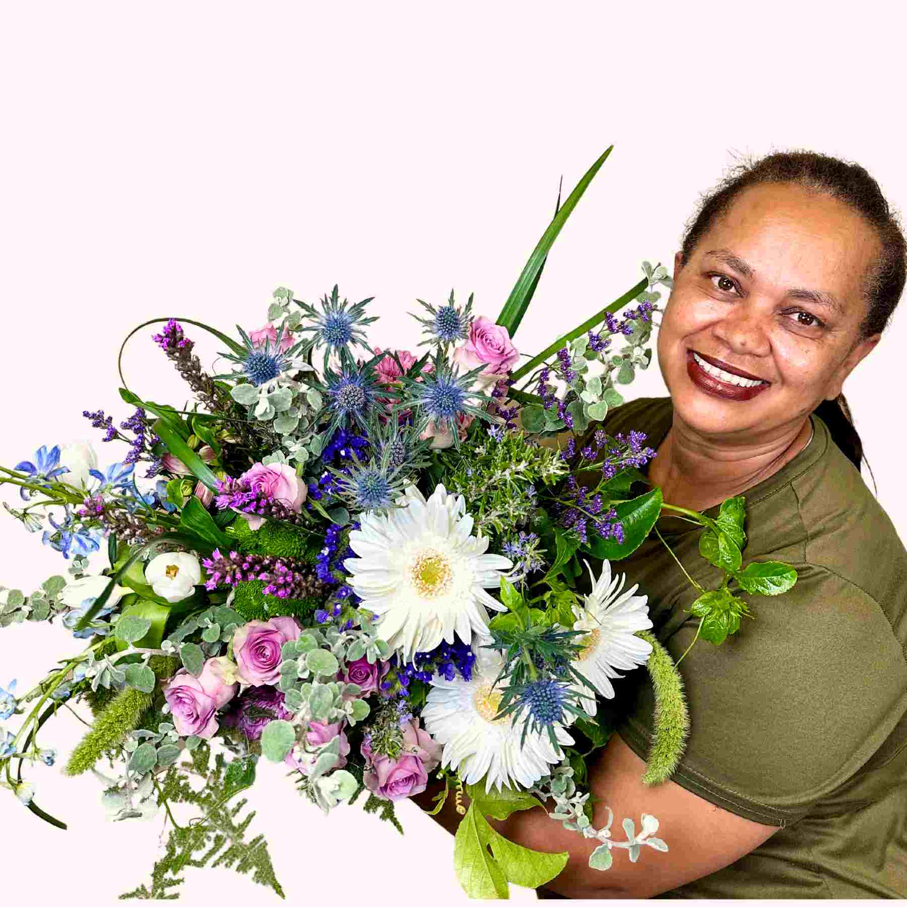 Smiling florist holding Joy's Flower Bouquet, a beautiful mix of white gerberas, lilies, and pastel roses, from Fabulous Flowers and Gifts.