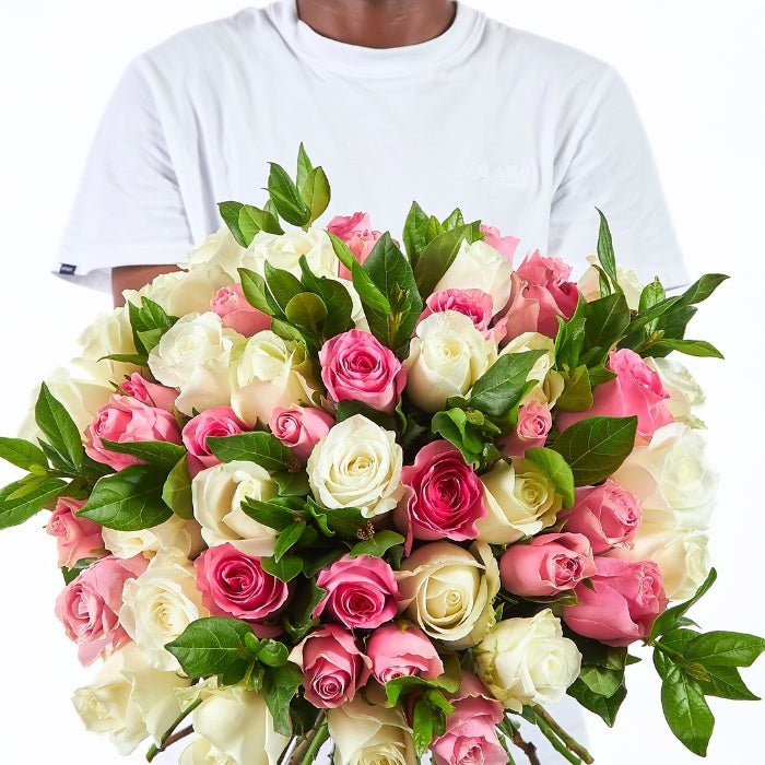Lush bouquet of pastel pink and white roses with green foliage, perfect for sending love and kindness.