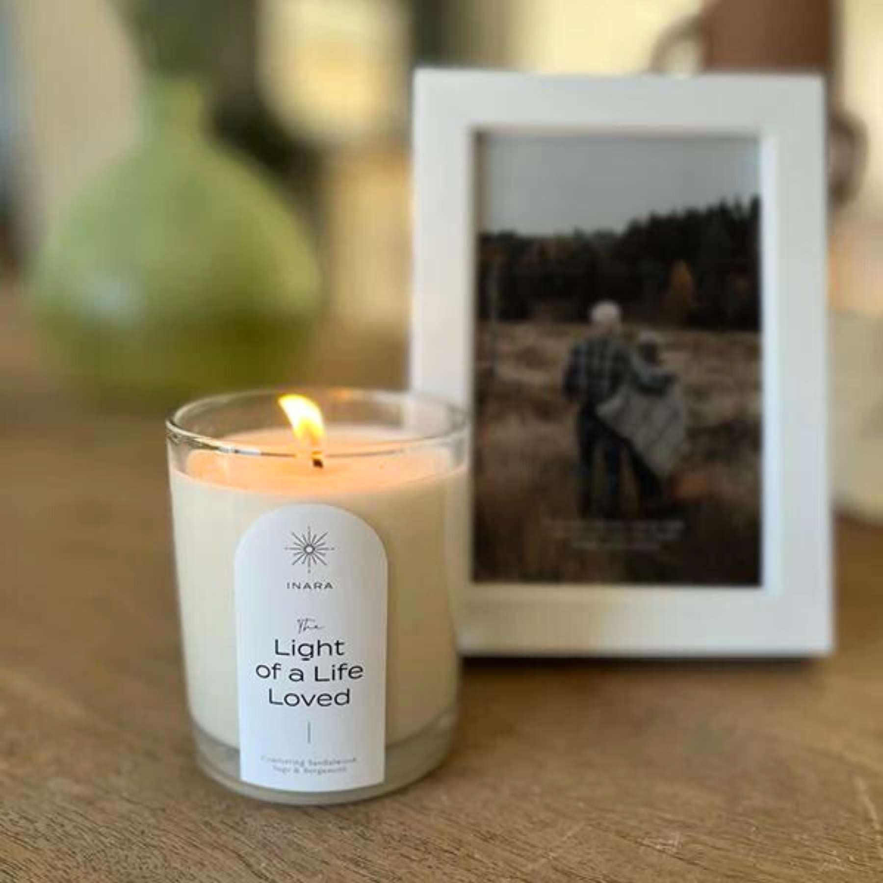 Elegant LACUNA Frame displaying a serene pastoral image, accompanied by a scented candle, part of the tasteful home decor collection at Fabulous Flowers and Gifts.
