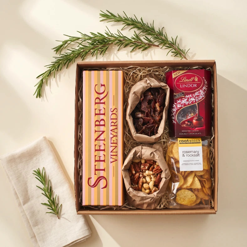 Let's Celebrate gift hamper flat-lay with Steenberg Vineyards wine, biltong, mixed nuts, Lindt Lindor and Rootstock rosemary rocksalt chips, Fabulous Flowers and Gifts