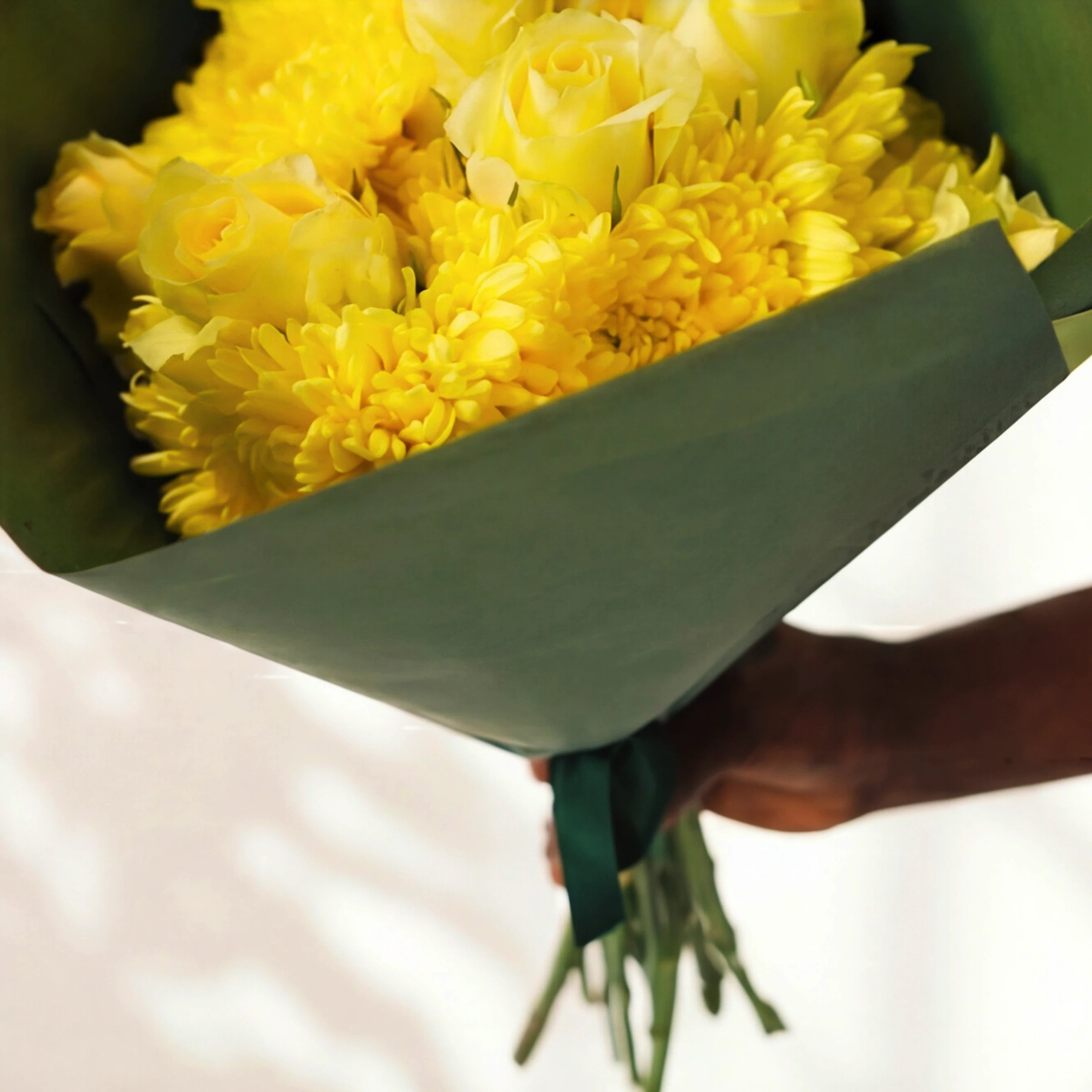 The Limoncello yellow roses bouquet from the side, yellow roses and chrysanthemums framed by green wrap