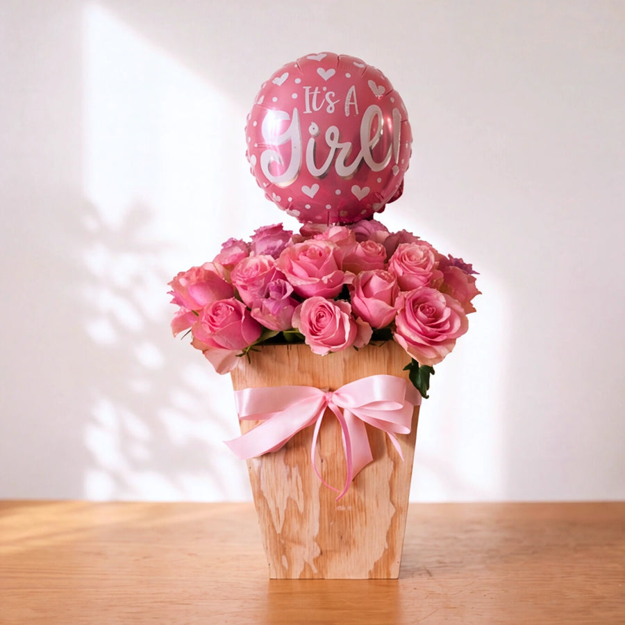 Little Sweetheart It's a Girl pink rose box with pink bow and It's a Girl balloon on a wooden table