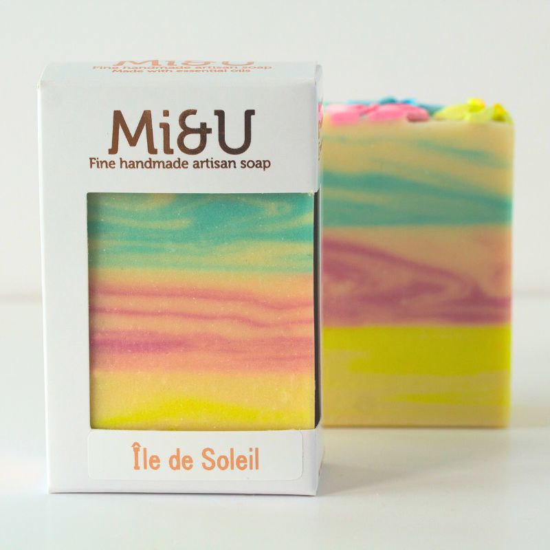 Packaged Île de Soleil artisan soap by Mi&U, featuring pastel stripes and tropical floral design.