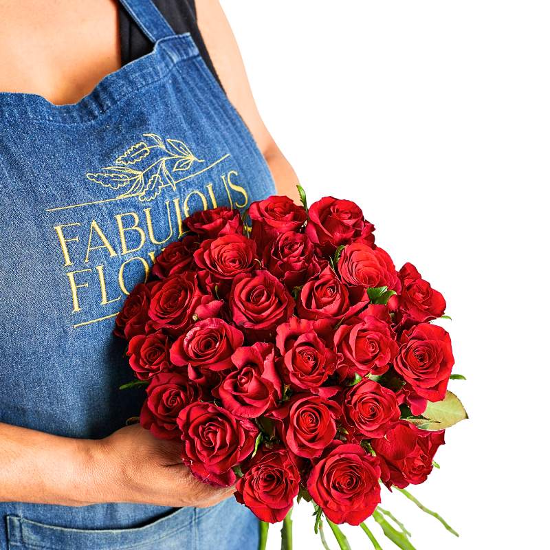 Person holding a bouquet of red roses wearing a blue apron with 'Fabulous Flowers' branding.