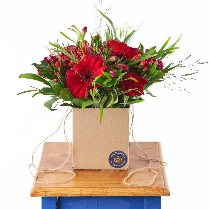 Eco-friendly Love's Charm Posy with vibrant red blooms in a kraft box by Fabulous Flowers & Gifts, perfect for romantic occasions.