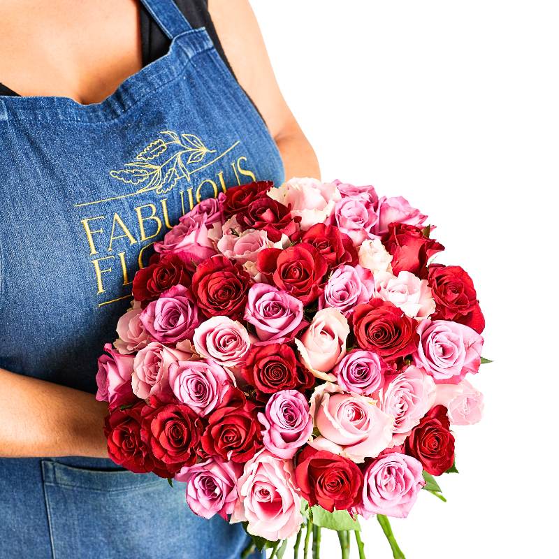 Person holding a bouquet of red and pink roses wearing a blue apron with 'Fabulous Flowers' branding.