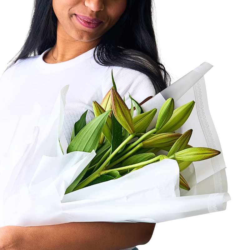 Close-up of long-stem white lilies held in arms, clean white petals and green foliage