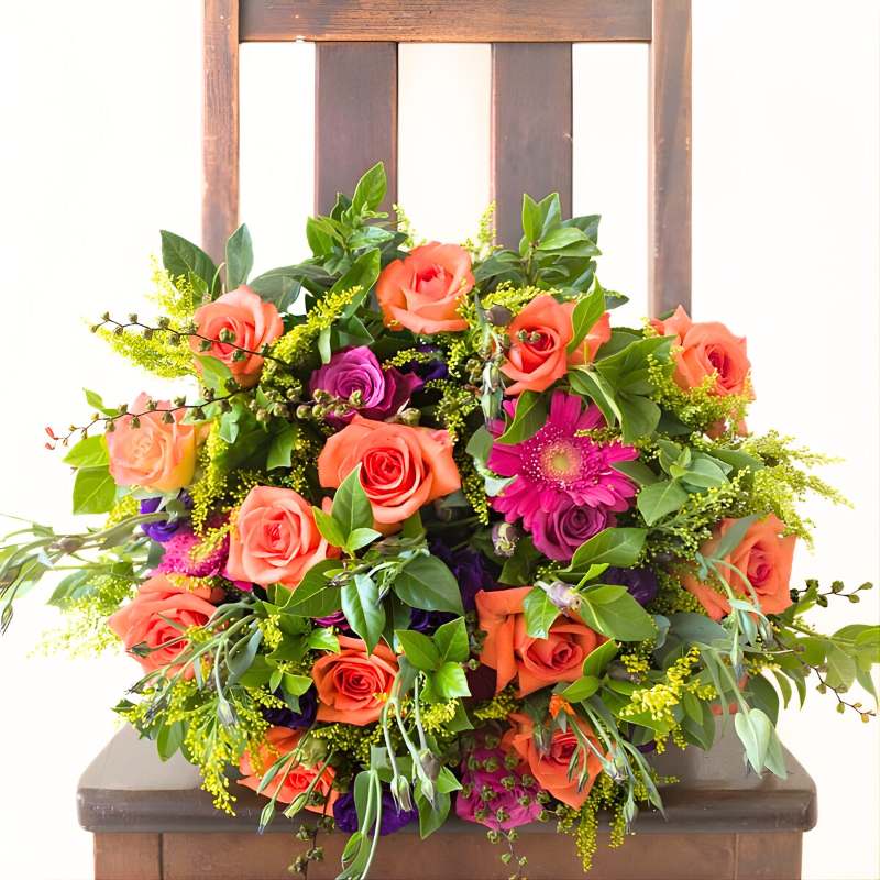 Colourful flower bouquet with orange, pink, and purple flowers on a wooden chair.