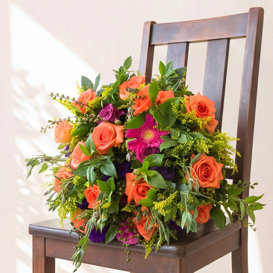 Orange and coral roses with a magenta gerbera and purple rose in the Lush and Lovely bouquet