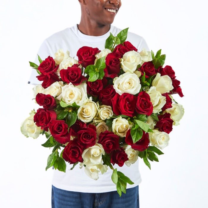 Midnight & Moonlight bouquet with red and white roses, hand-held by a smiling person in a white shirt.