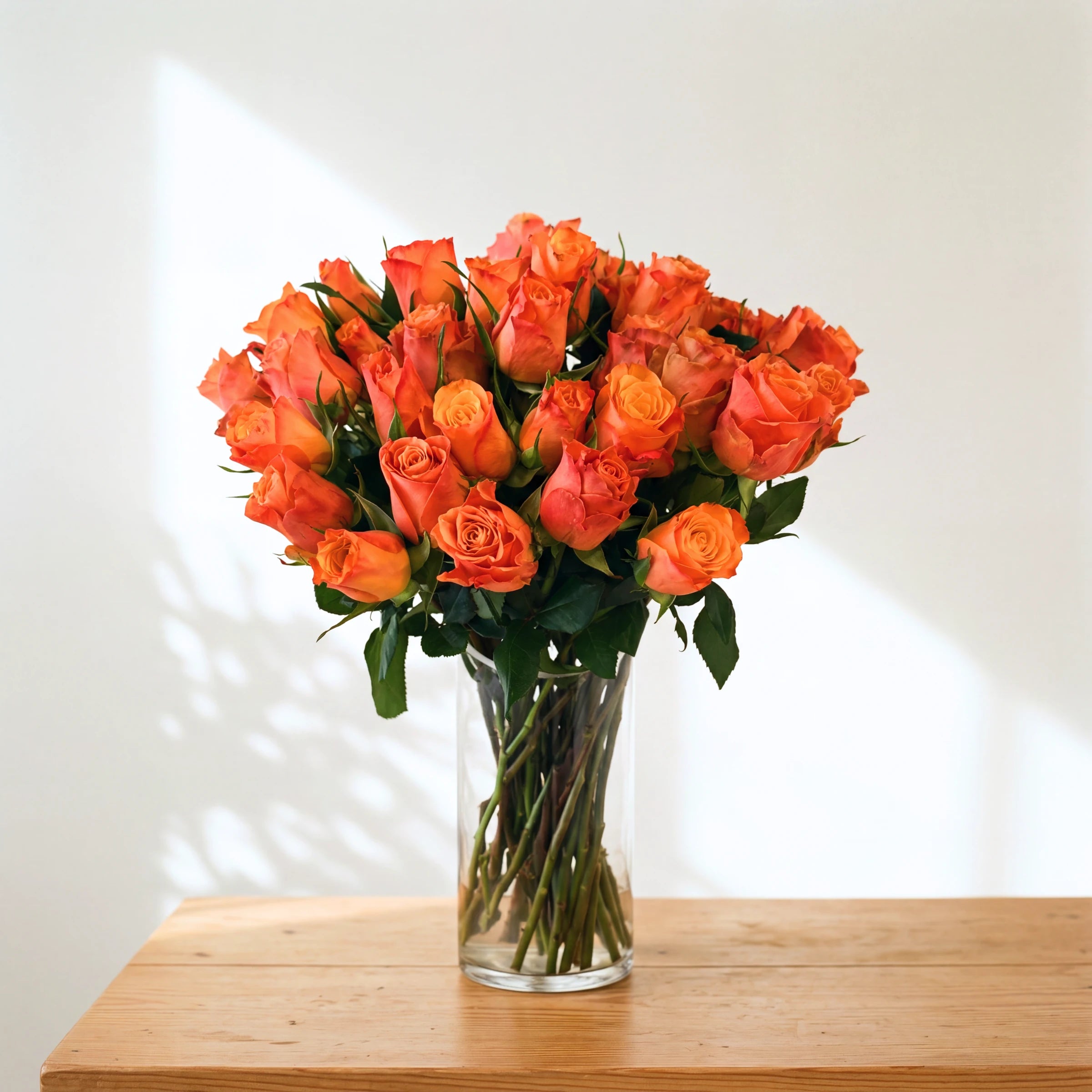 Mimosa vase of orange roses, a lush full glass vase of bright orange and gold roses, ready to display
