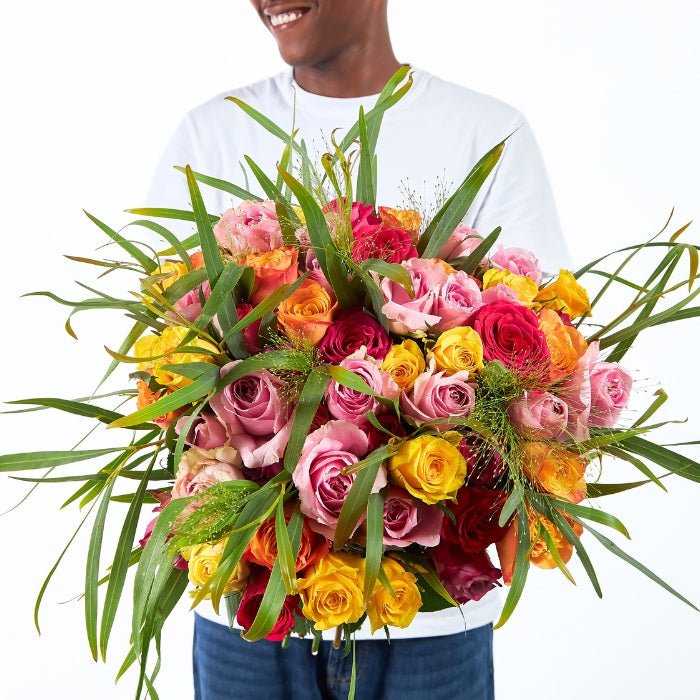 Mixed Rose Bouquet – vibrant pink, yellow, orange and red roses hand-tied with greenery by Fabulous Flowers & Gifts.