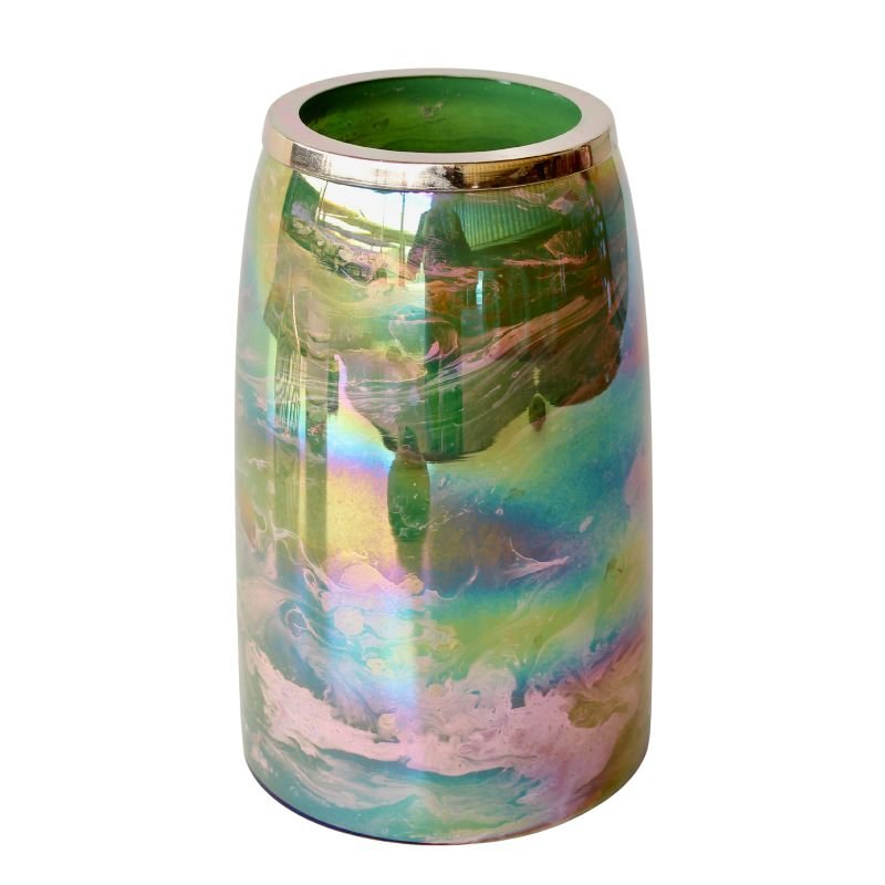 Iridescent candle holder with a green candle on a white background