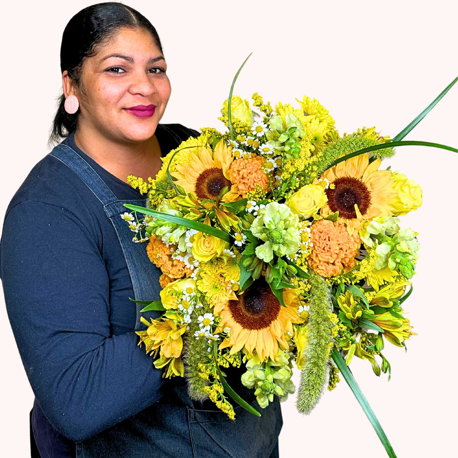Smiling florist holding Natasha's Flower Bouquet, featuring vibrant sunflowers and yellow blooms, from Fabulous Flowers and Gifts.
