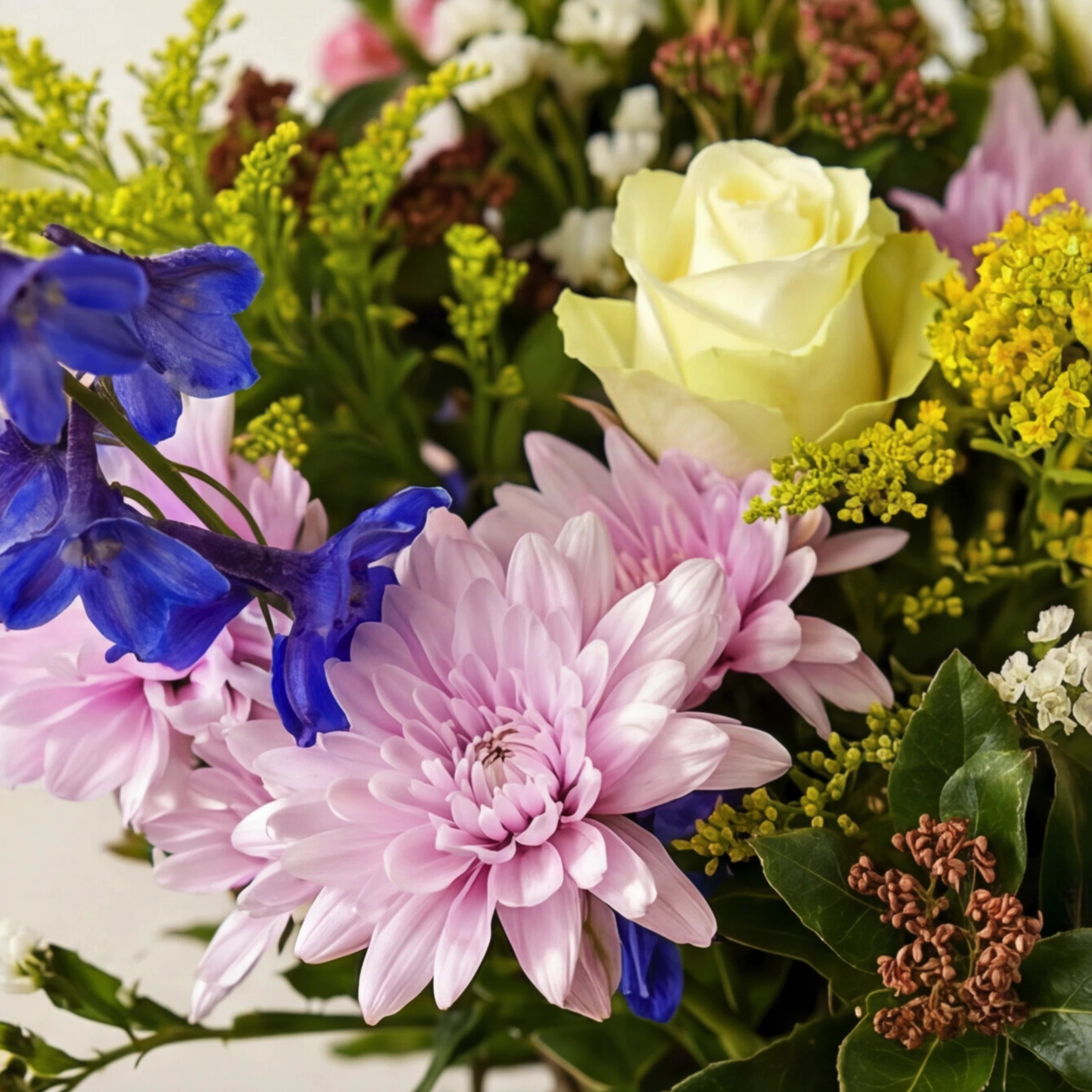 Close-up of New Baby Jar arrangement showing the soft pink chrysanthemum, cream white rose, blue delphinium and yellow solidago in pastel newborn-friendly tones, from Fabulous Flowers.