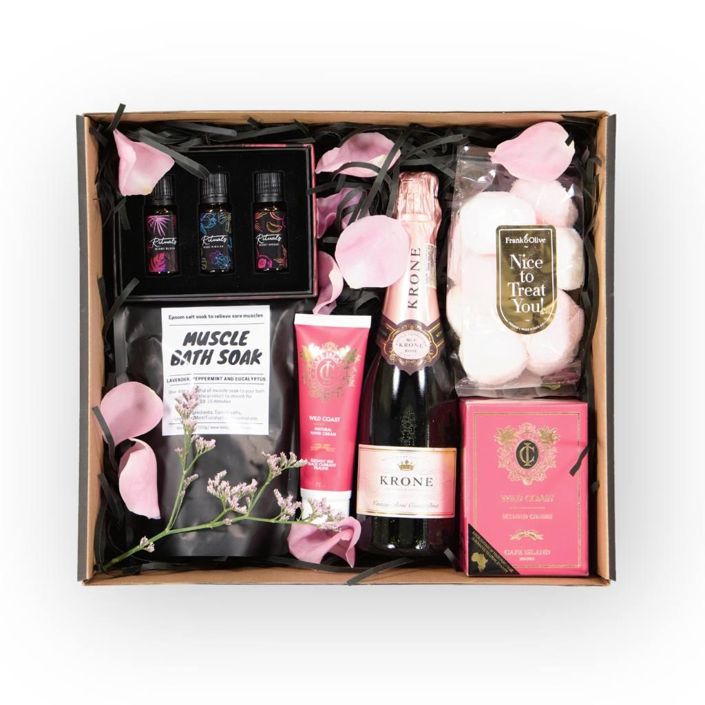 The Pamper and Indulge Gift Box for Girls includes Muscle Bath Soak, Krone Brut Rose MCC 375ml, Cape Island Wild Coast Hand Cream and Candle, Frank & Olive marshmallows and a trio of Aura Rituals Essentials Oils - Fabulous Flowers