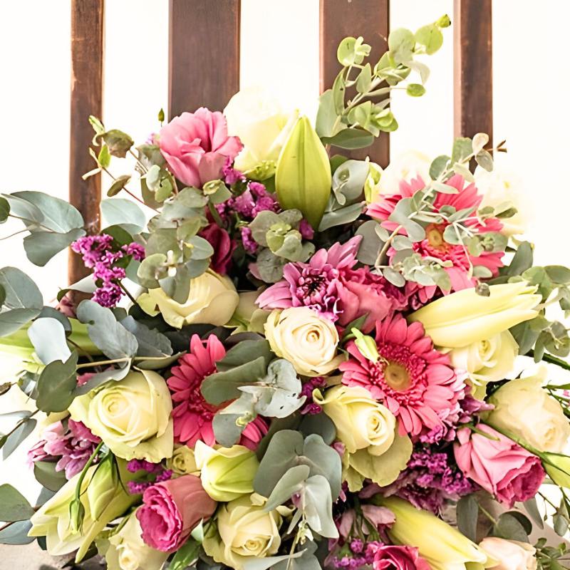 Bouquet of flowers with pink, white and green colors against a wooden background.