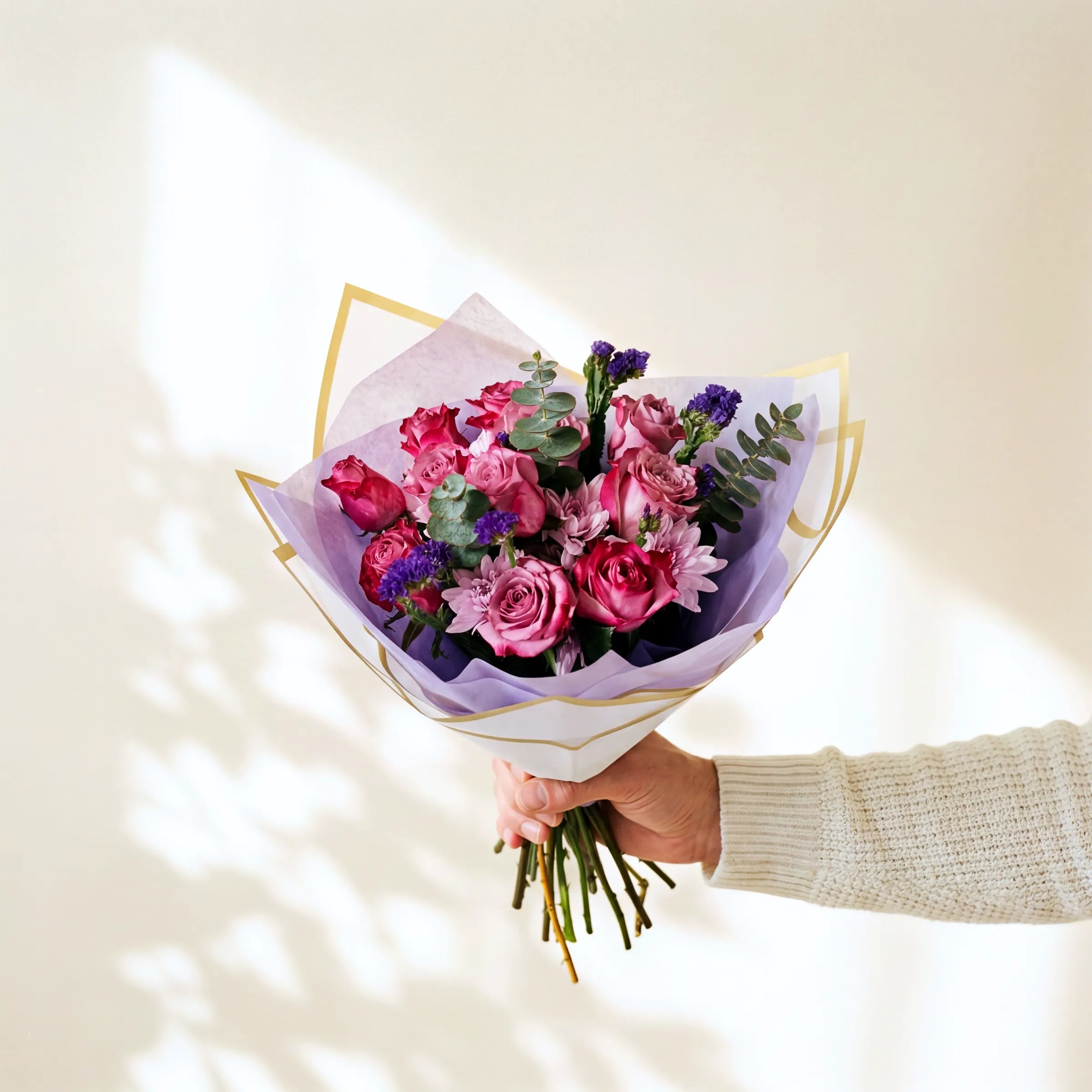 Bouquet of flowers held by a person against a light background