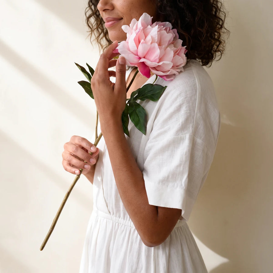 Woman holding a single pink peony artificial flower from Fabulous Flowers