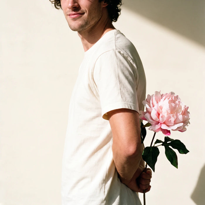 Man hiding a pink peony artificial flower behind his back as a surprise gift