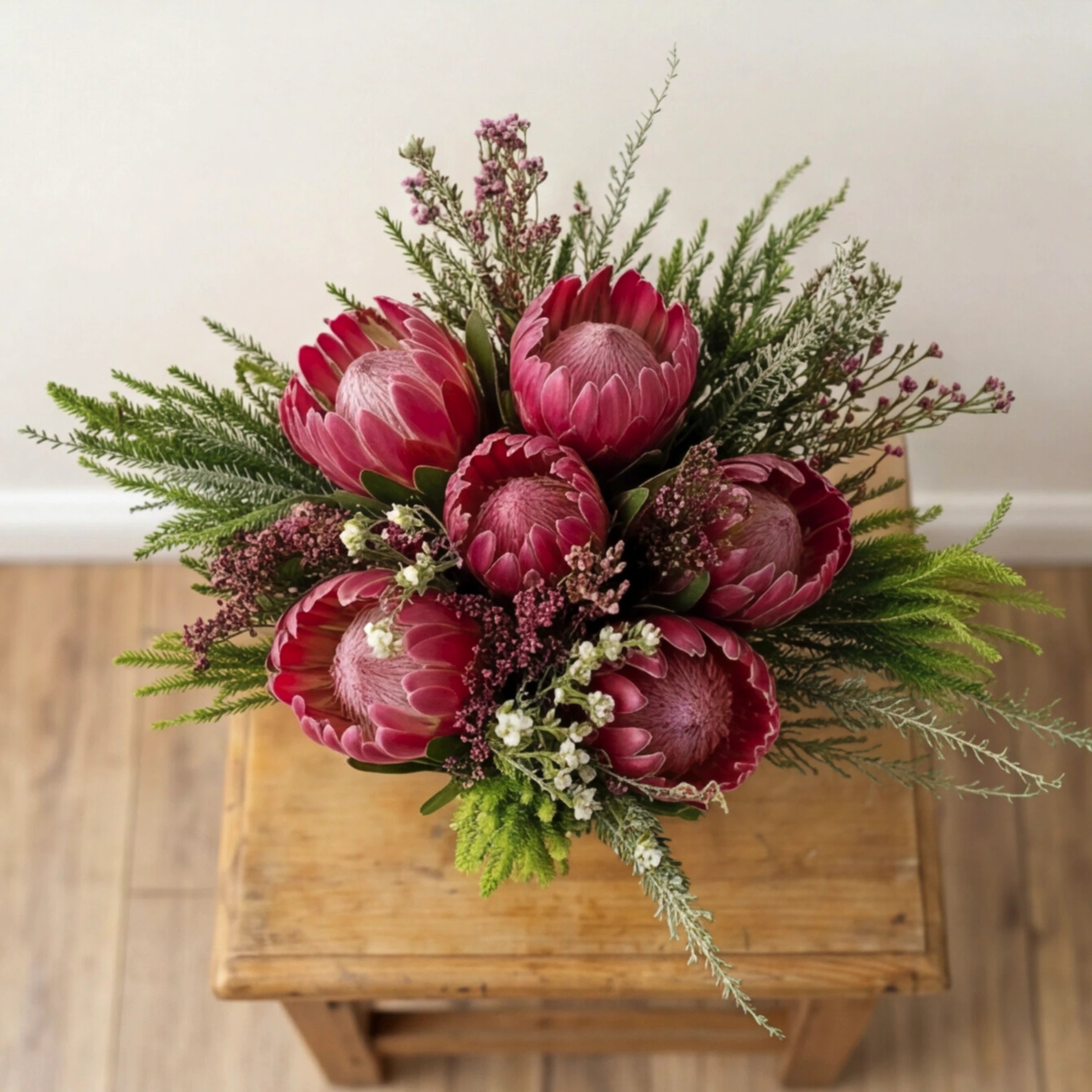 Top view of Proteas in a Jar by Fabulous Flowers South Africa, six Pink Ice proteas, pink fynbos waxflower, erica and restio hand-styled around the centre of a twine-tied glass jar for masculine gifts, corporate gifting and Cape Town flower delivery