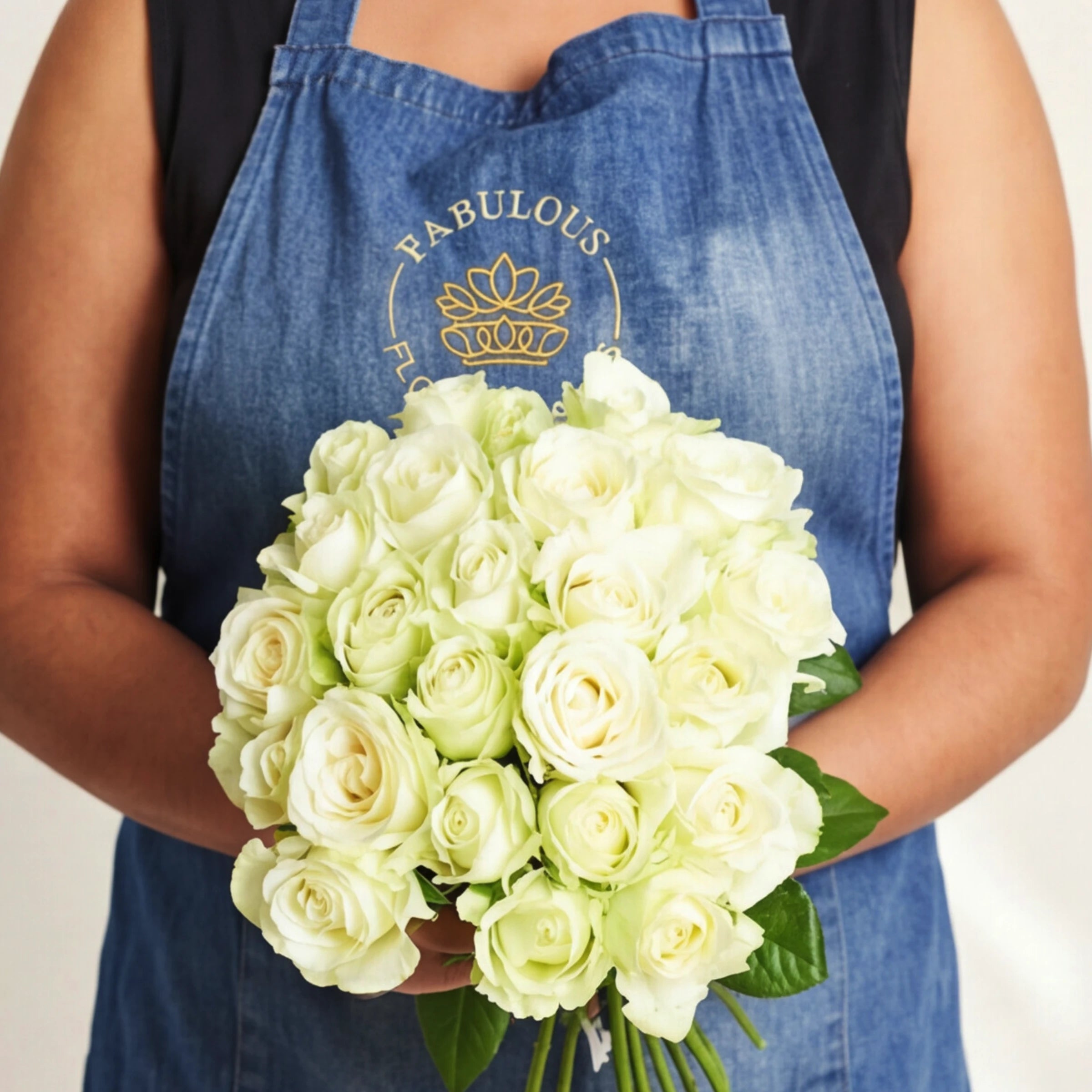 A florist holding a full bunch of white and cream Pure Snow roses in a Fabulous Flowers apron.