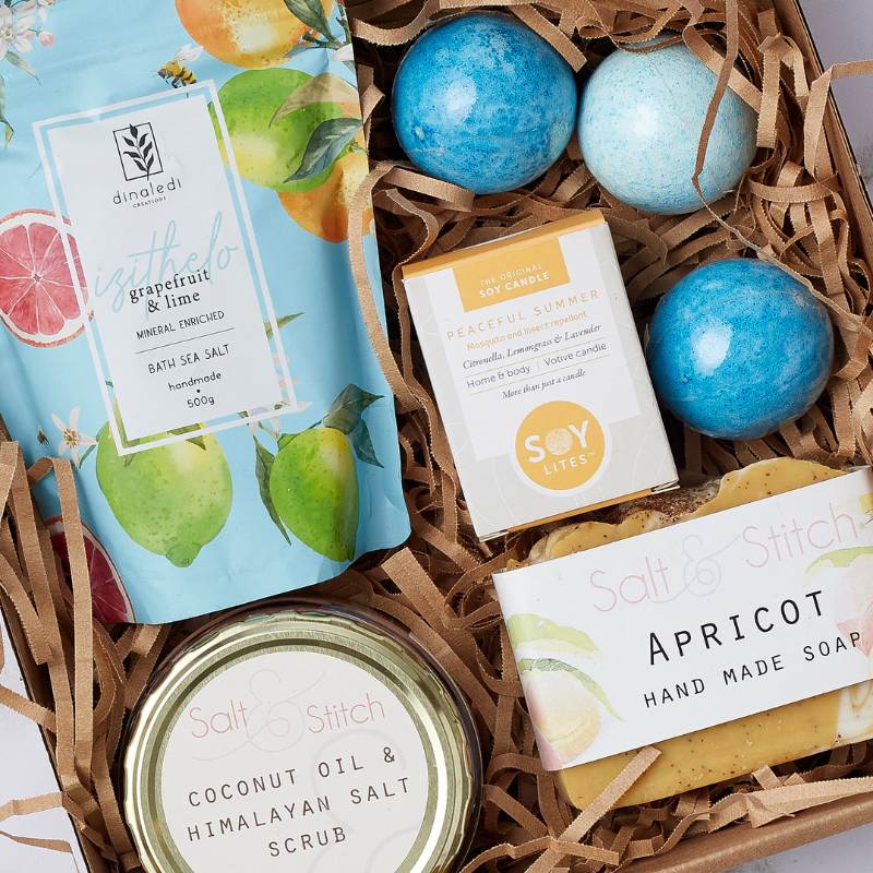 Close-up of the Relax and Unwind Gift Box with bath salts, coconut oil and Himalayan salt scrub, apricot handmade soap, bath bombs, and a soy candle.