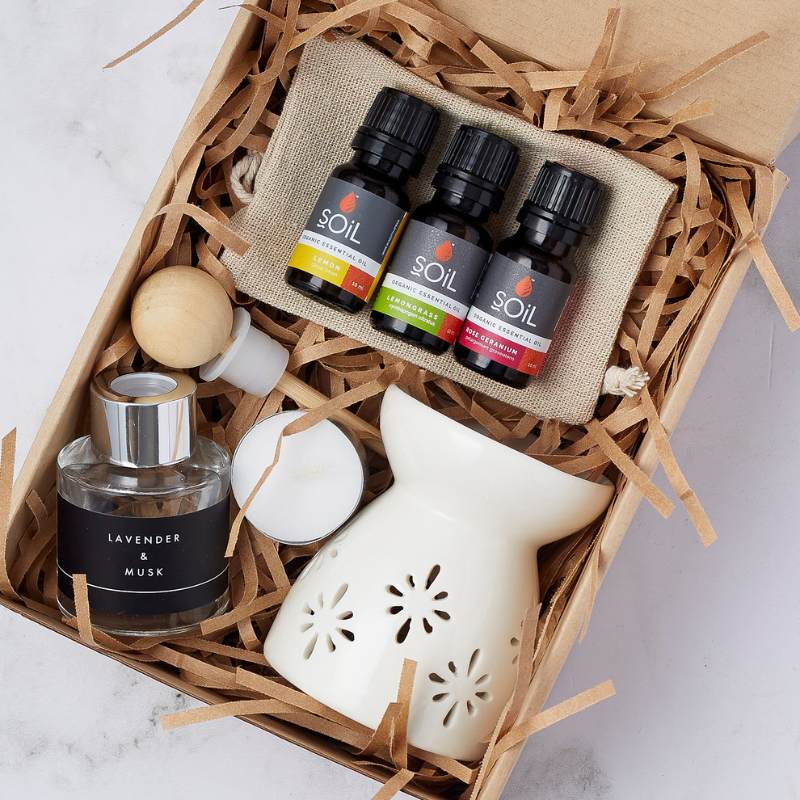 Close-up of the Rose Garden Indulgence Set featuring organic essential oils, a ceramic diffuser, a lavender and musk fragrance, and a candle.
