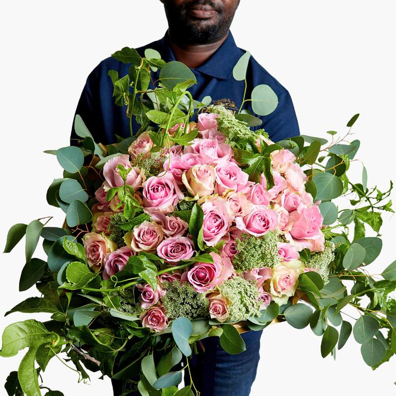 "Rose Garden Bouquet featuring an elegant arrangement of soft pink roses, lush green foliage, and delicate accents, held by an individual - Fabulous Flowers & Gifts.