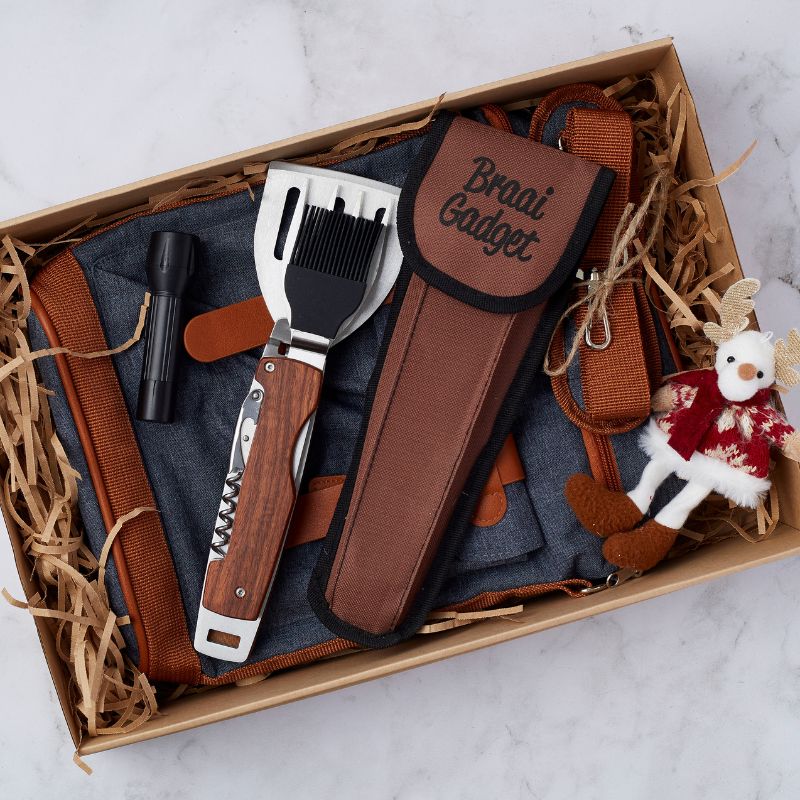 Santa’s Braai Essentials Gift Set with multi-functional braai gadget, denim apron, flashlight, and a festive plush reindeer.