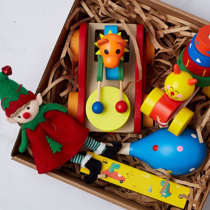 Santa's Little Toy Box with wooden push toys, stacking caterpillar, musical shaker, sliding whistle, and festive elf doll.