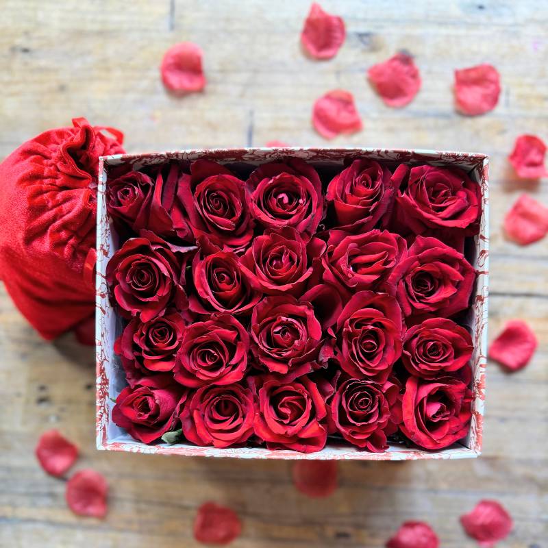 Top view of the Scarlet Sonnets gift box, featuring radiant red roses arranged perfectly, surrounded by scattered rose petals - Fabulous Flowers & Gifts.