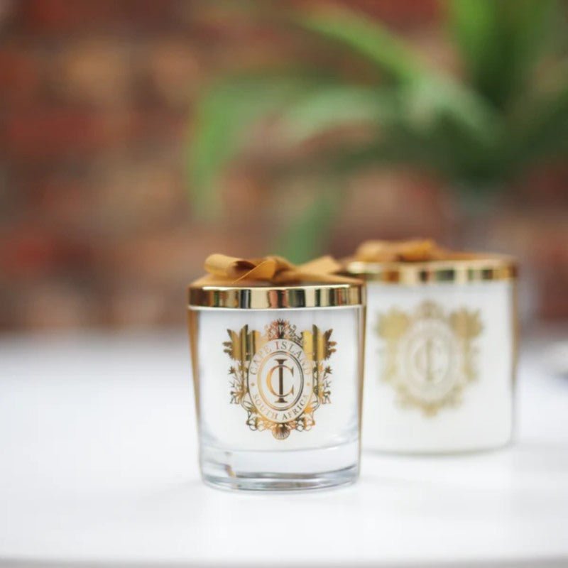 Two decorative candles with gold accents on a blurred background