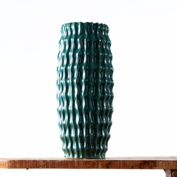 Sea Ripple Tall Vase in deep teal with a unique, wavy texture design, standing on a wooden surface, embodying oceanic aesthetics.