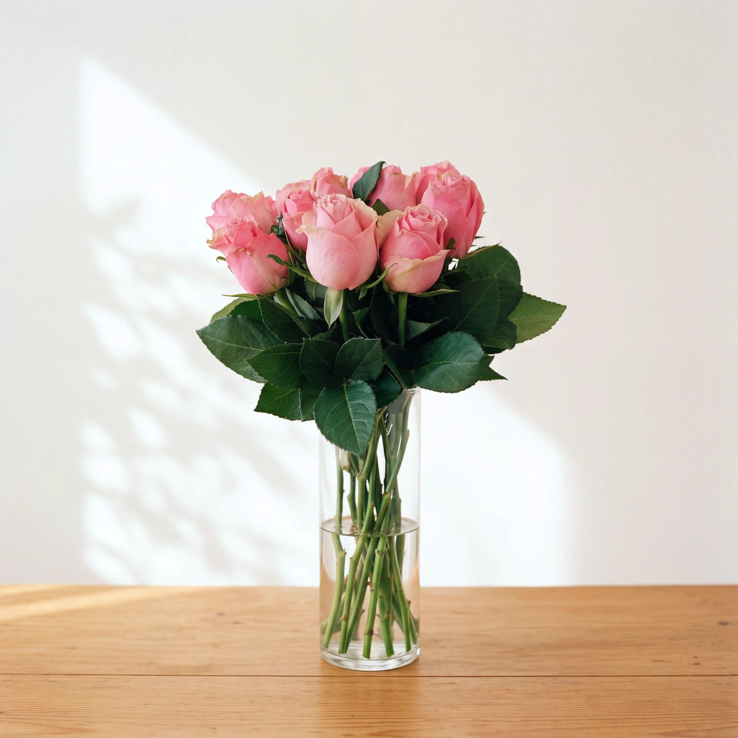 Sherbert, a dozen soft pink roses in a clear glass vase on a wooden table, by Fabulous Flowers