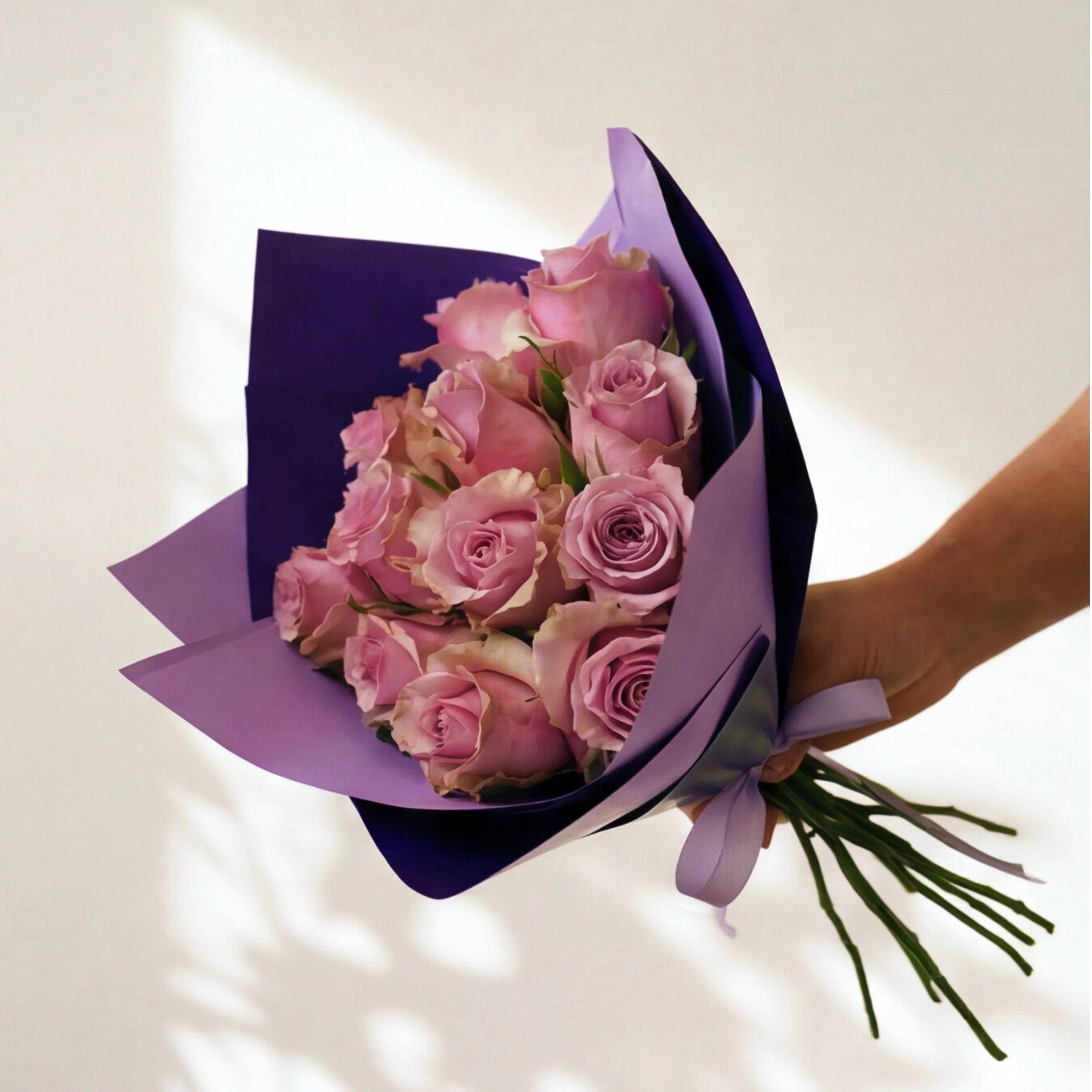 Smitten, a dozen lavender roses wrapped in two-tone purple with a lilac ribbon, by Fabulous Flowers