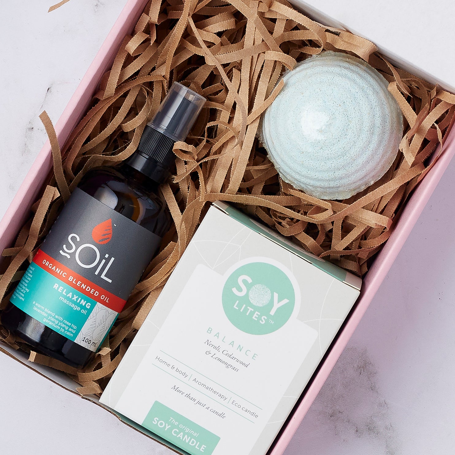 Close-up of the Soothing Balance Gift Set featuring relaxing massage oil, a balance soy candle, and a soothing bath bomb.