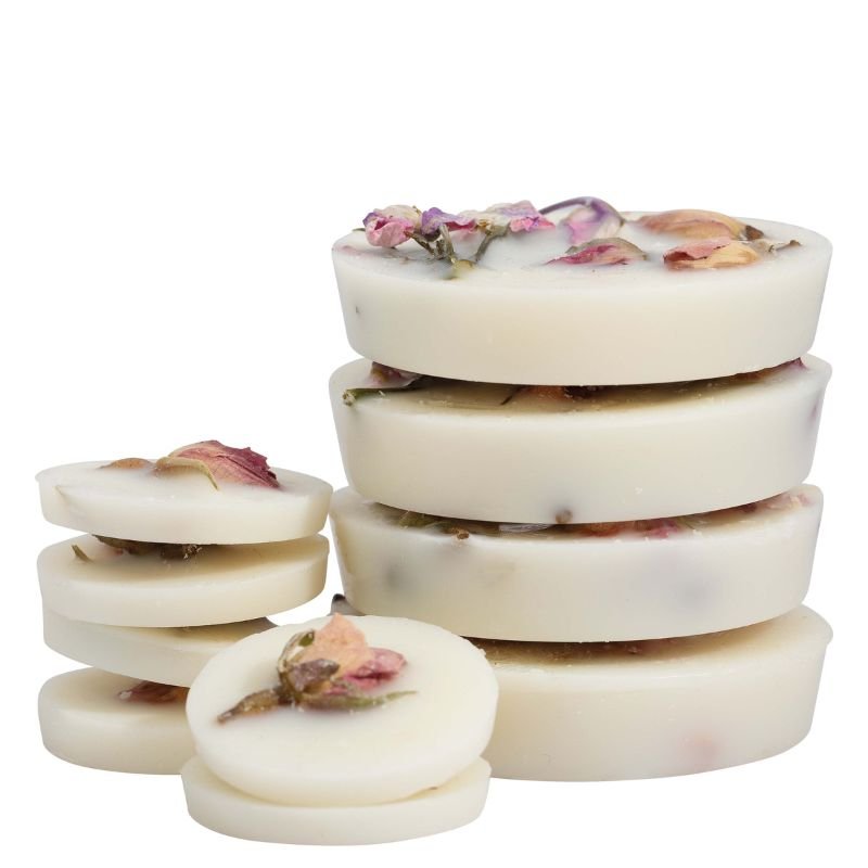 Stack of white soap bars with floral petals on a white background