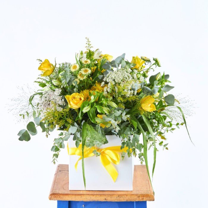 Sundance Bloom Box featuring a vibrant array of yellow roses and mixed wildflowers in a white box tied with a yellow ribbon.