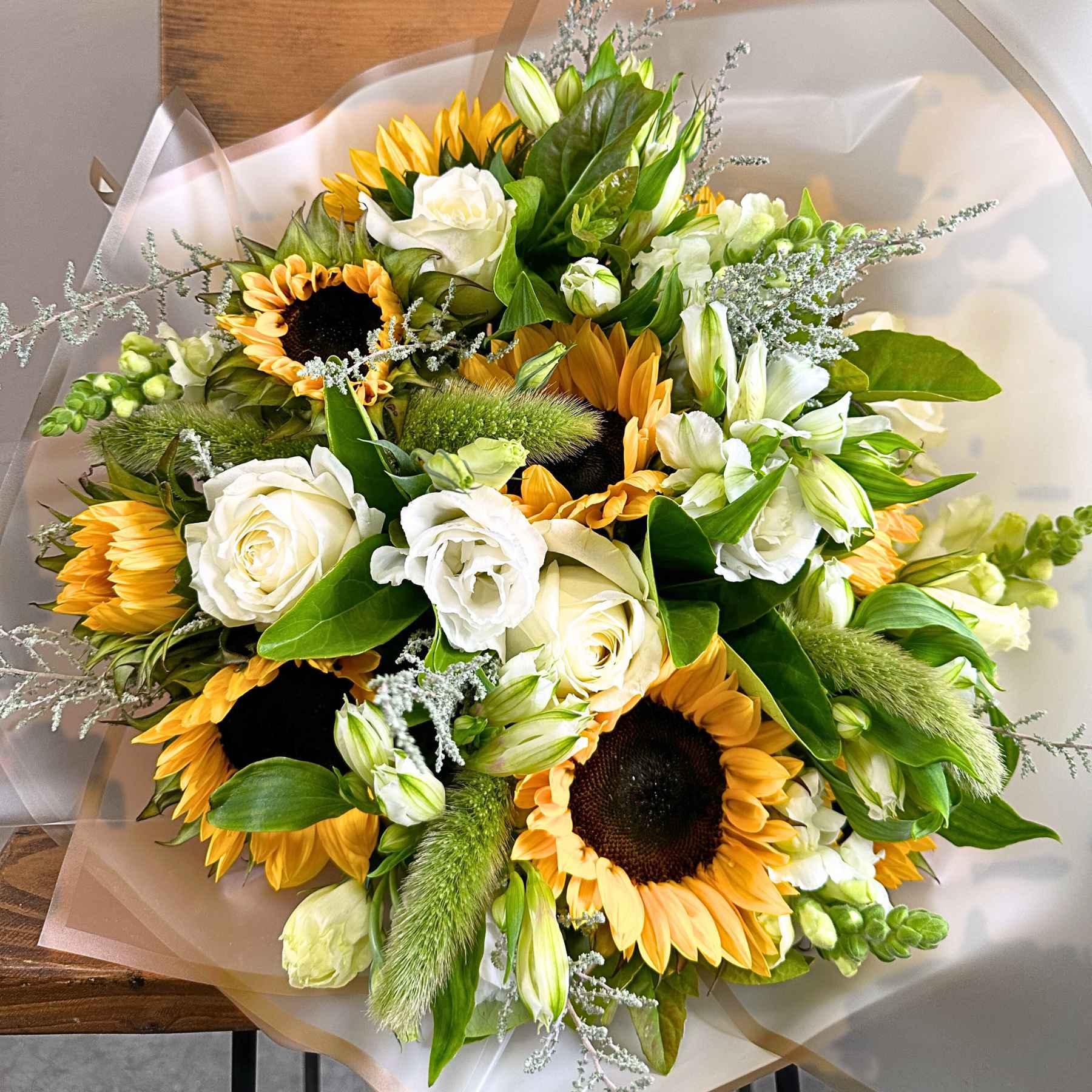 A vibrant Sunflower Garden Flower Bouquet featuring bright sunflowers, delicate white roses, and lush greenery, perfectly arranged to capture the essence of summer. This bouquet is part of the Sunflower Garden Flower Bouquet Collection by Fabulous Flowers and Gifts, designed to bring joy and beauty to any occasion.
