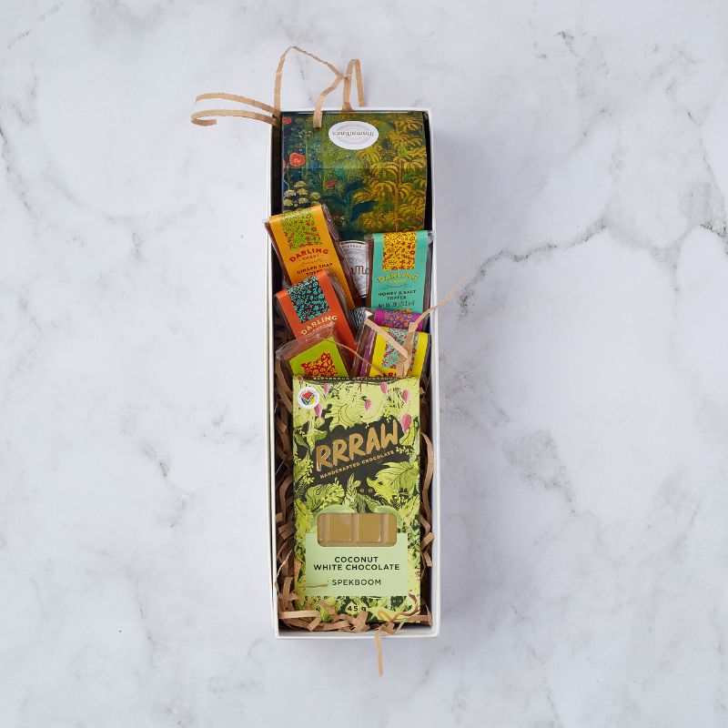 A gift box featuring an assortment of gourmet treats including Darling Sweet toffees and Rrraw handcrafted coconut white chocolate, arranged with decorative crinkle paper.