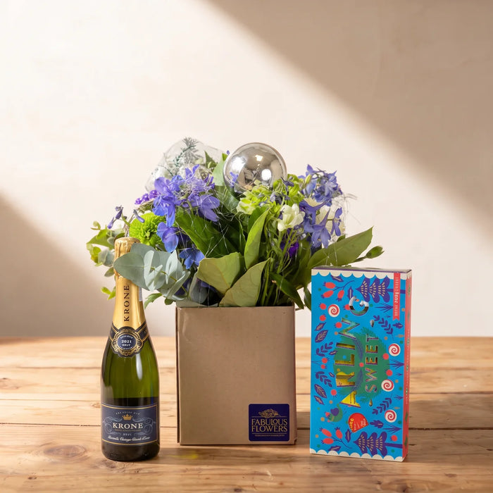 Small kraft box posy of blue delphiniums, green hydrangea and a silver bauble beside a half bottle of Krone Borealis and a blue box of Darling Sweet toffee, Fabulous Flowers South Africa
