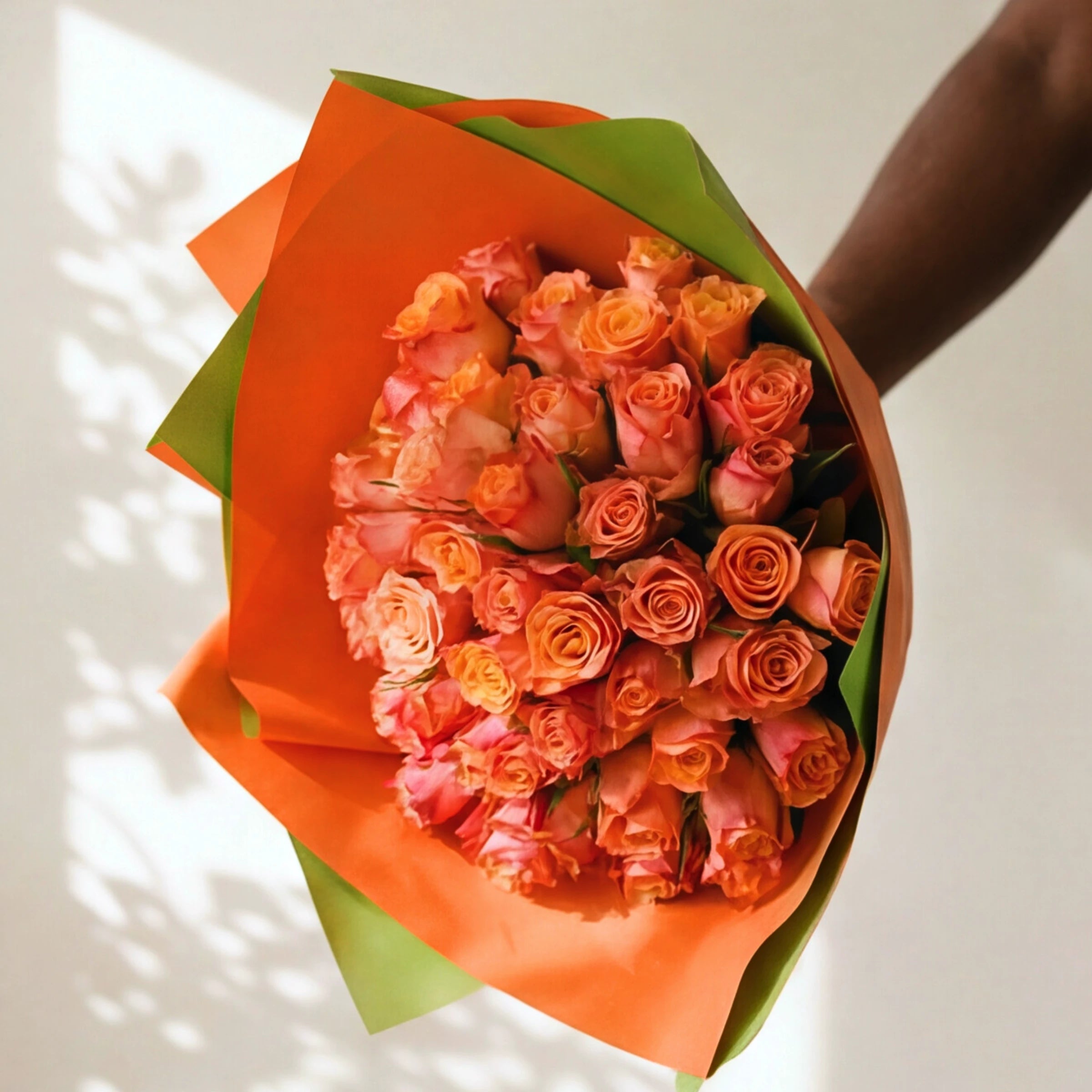Overhead view of the Tangelo orange rose bouquet, vivid orange roses in bright orange and green wrap.