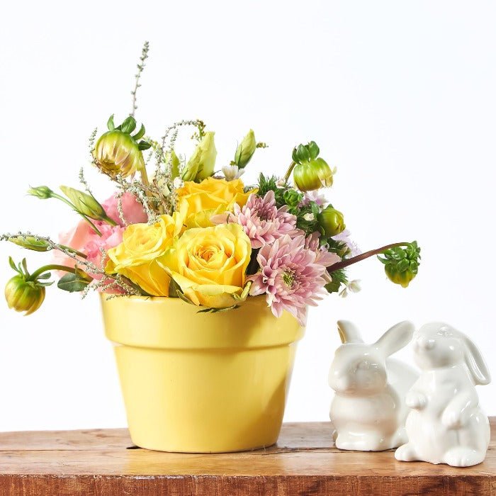 The Garden of First Light - Fabulous Flowers & Gifts close-up of yellow roses, pink blooms and white bunny décor in a floral pot.