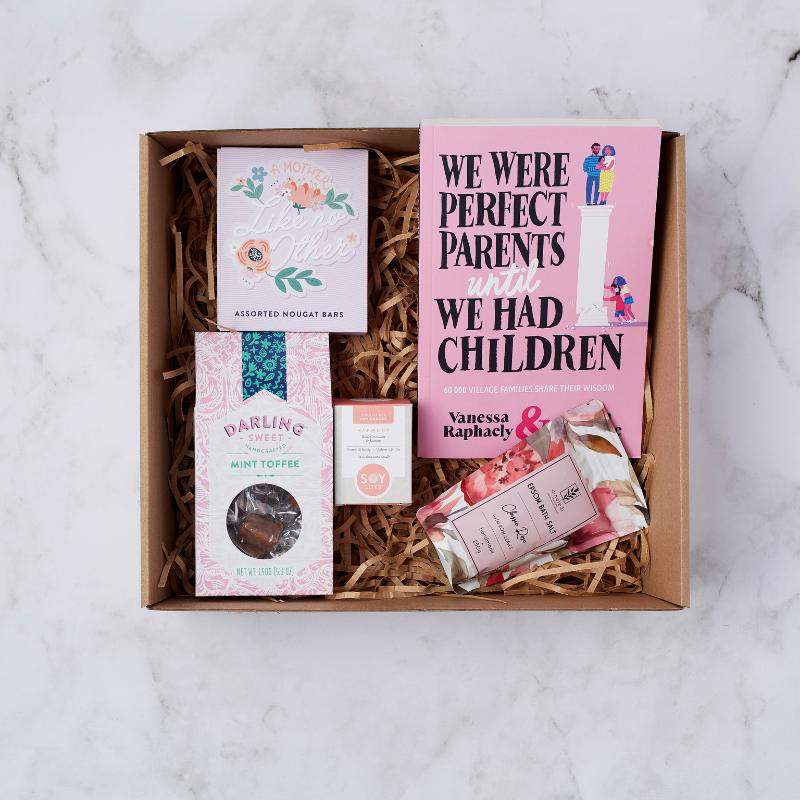 The Perfect Parent Pamper Gift Box with a parenting book, nougat bars, mint toffee, soy candle, and Epsom bath salts in floral packaging.