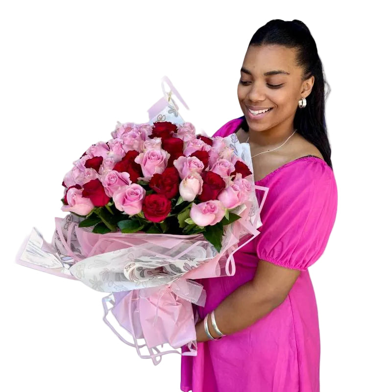 Elegant bouquet of pink and red roses in a smiling woman’s hands, wrapped with floral detailing and pink accents.
