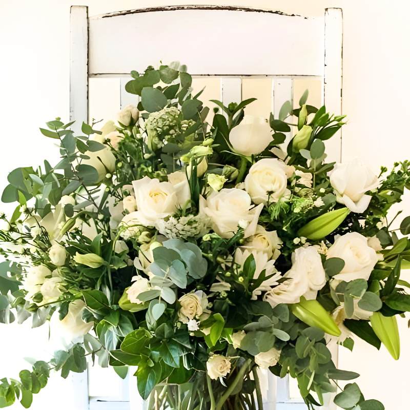 Glass vase arrangement of white and green flowers in a clear vase against a white background