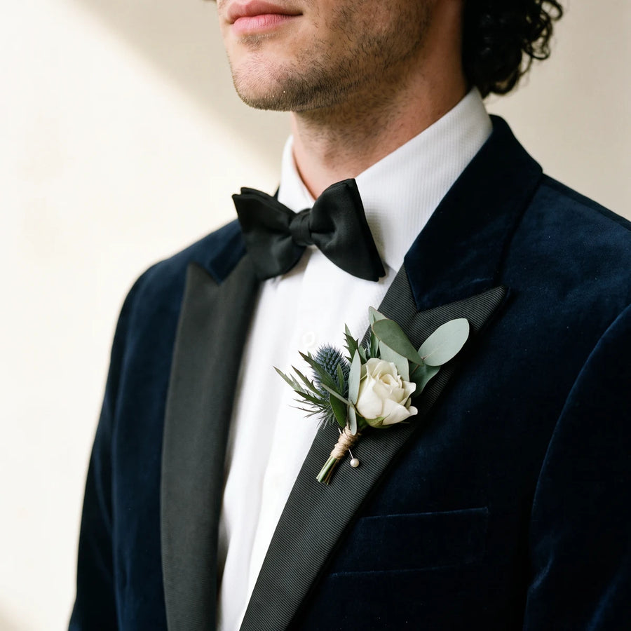 Man in a navy velvet dinner jacket and black bow tie wearing a blue thistle boutonniere, Fabulous Flowers South Africa