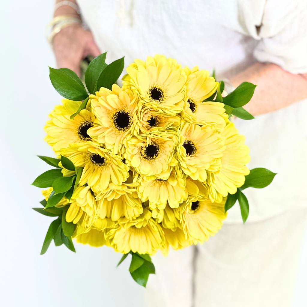Bouquet of yellow flowers held by a person on a white background