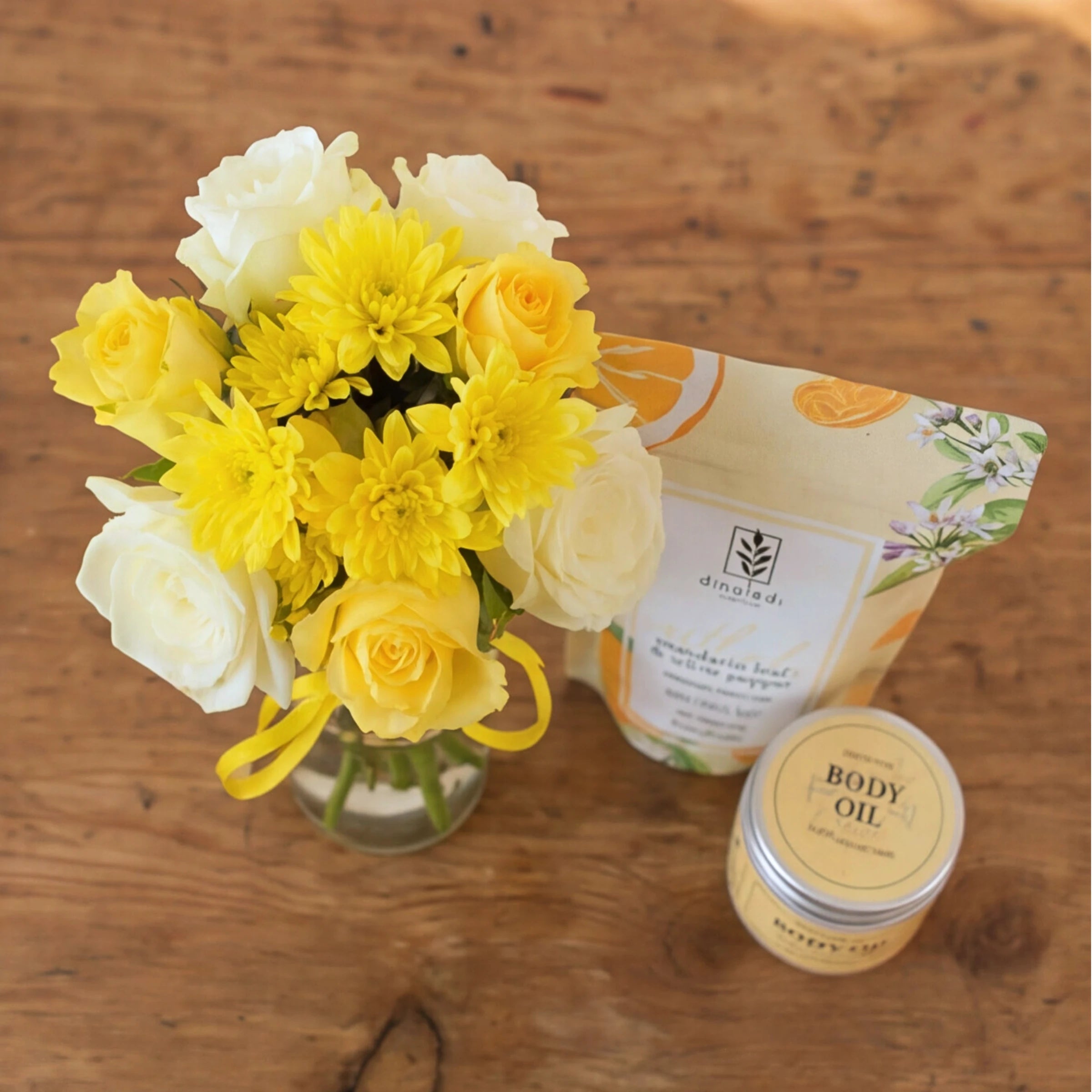 Top-down view of the Zest & Rest pamper hamper posy of yellow roses and chrysanthemums, with bath salts and body oil